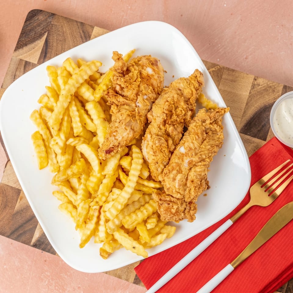 Crispy fried chicken tenders and crinkle-cut fries on a white plate with a side of ranch.