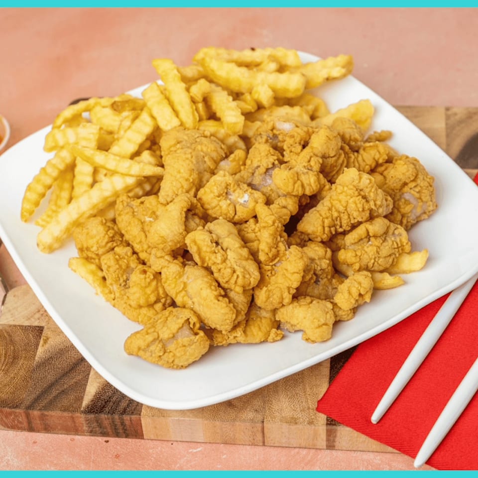 A white plate holds a generous serving of golden-brown fried Snappers fish and crinkle-cut fries.