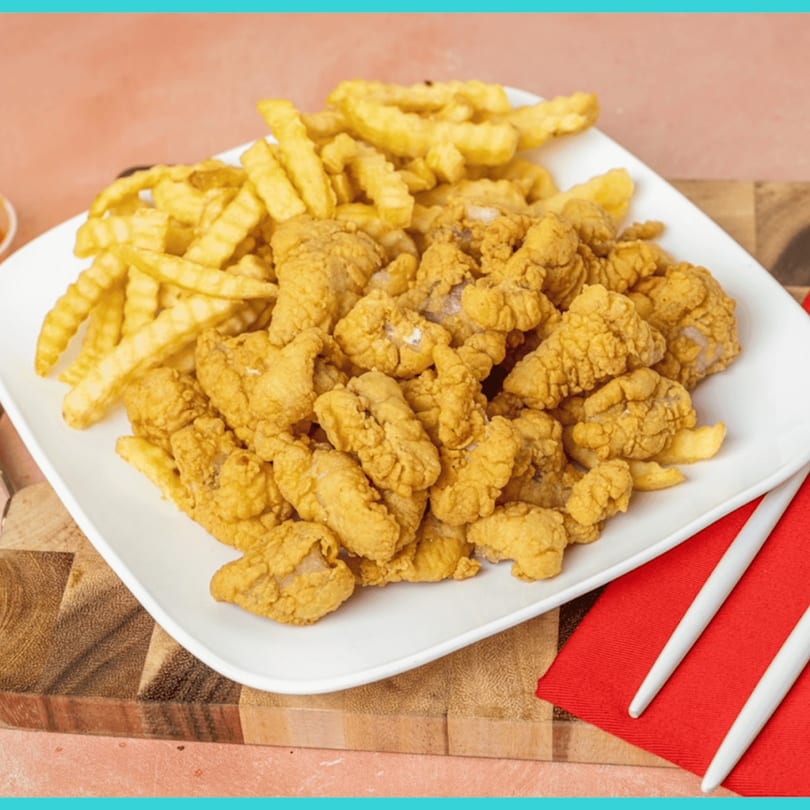 A white plate holds a generous serving of golden-brown fried Snappers fish and crinkle-cut fries.