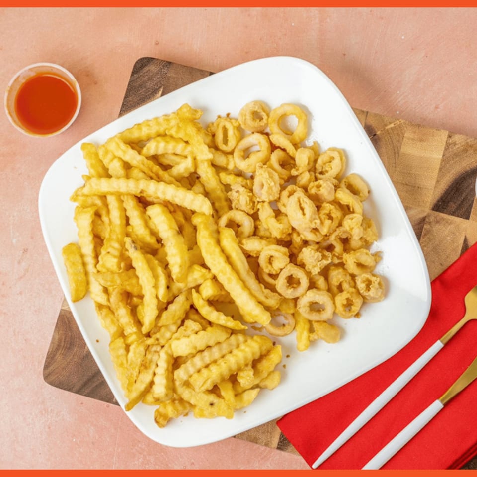 A white plate with Snappers' crispy calamari and crinkle-cut fries, with a side of hot sauce.